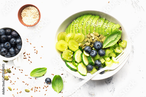 Green vegetables fruit detox balance salad bowl. Avocados, cucumbers, cherry tomatoes, blueberries, celery, grapes. Juicy cream crispy dish without meat photo