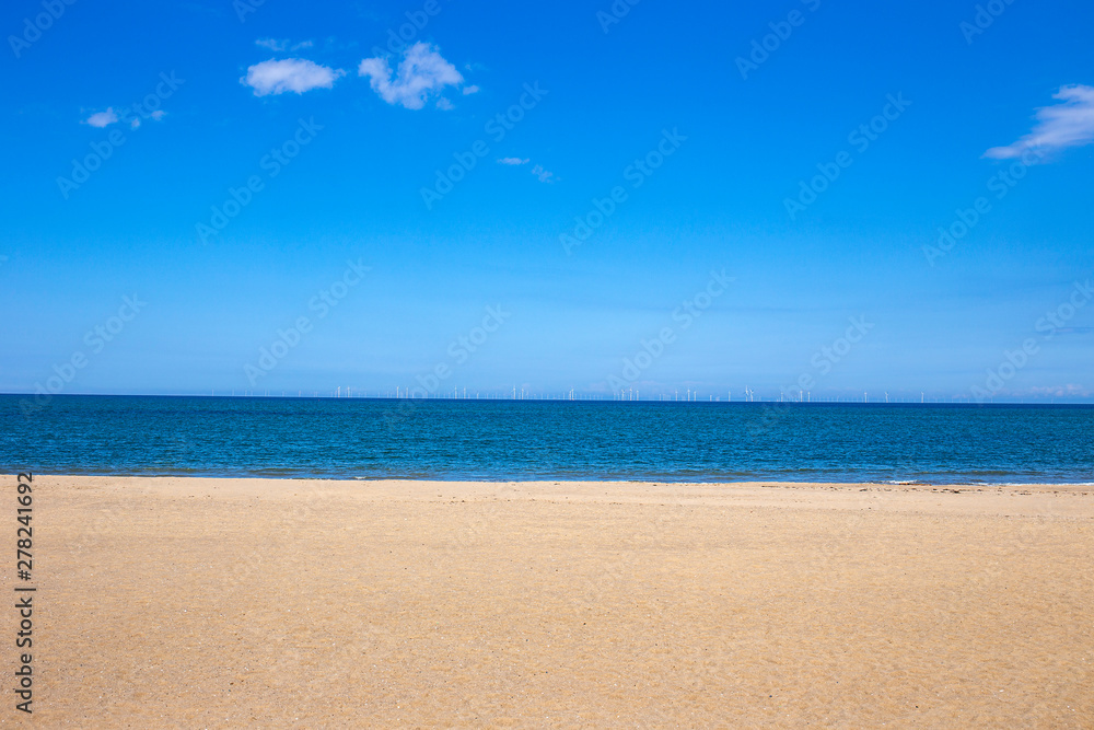 White sandy beach with ocean and deep blue sky in North Wales UK