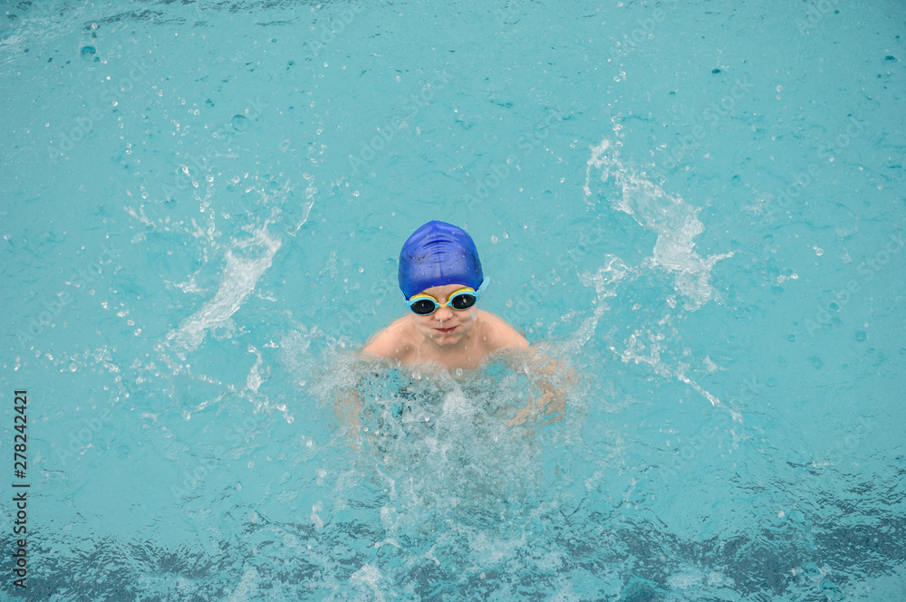 top view of a 7-year boy playing and swimming in the swimming pool