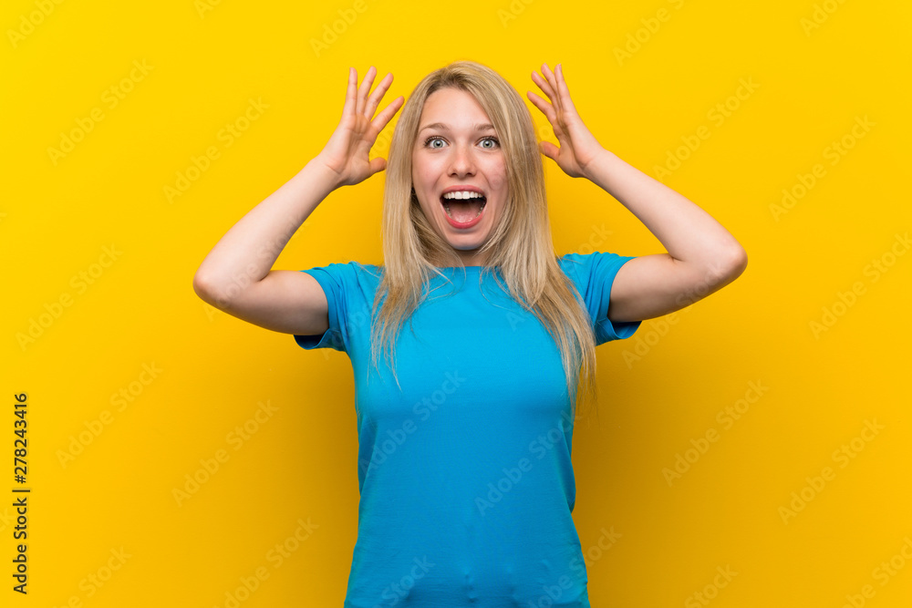 Young blonde woman over isolated yellow background with surprise expression Young blonde woman over isolated yellow background with surprise expression