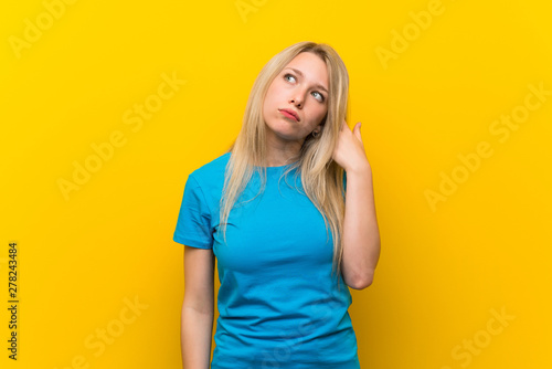 Young blonde woman over isolated yellow background with problems making suicide gesture