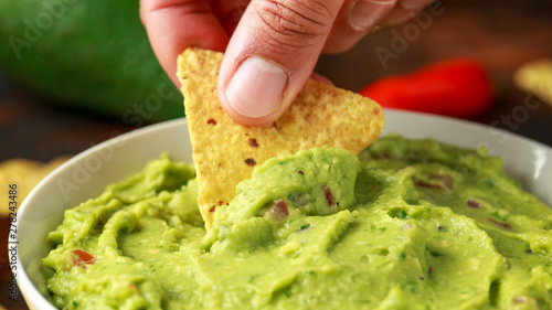 Man hand is picking some guacamole dip with nachos chip. Healthy Vegan, Vegetables food. photo