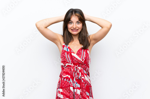 Caucasian girl in red dress over isolated white wall frustrated and takes hands on head © luismolinero