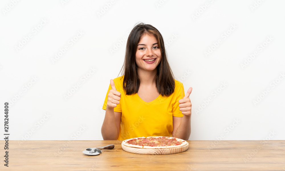 Caucasian girl with a pizza giving a thumbs up gesture