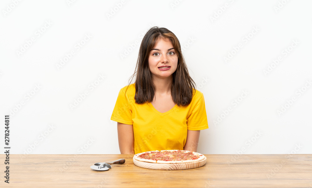 Caucasian girl with a pizza having doubts and with confuse face expression Caucasian girl with a pizza having doubts and with confuse face expression