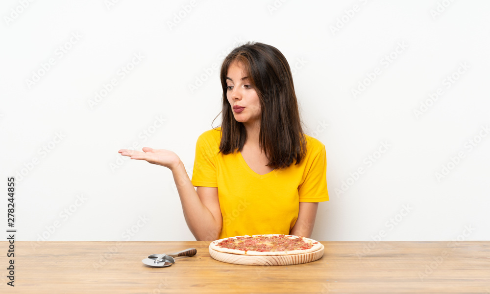 Caucasian girl with a pizza holding copyspace imaginary on the palm Caucasian girl with a pizza holding copyspace imaginary on the palm