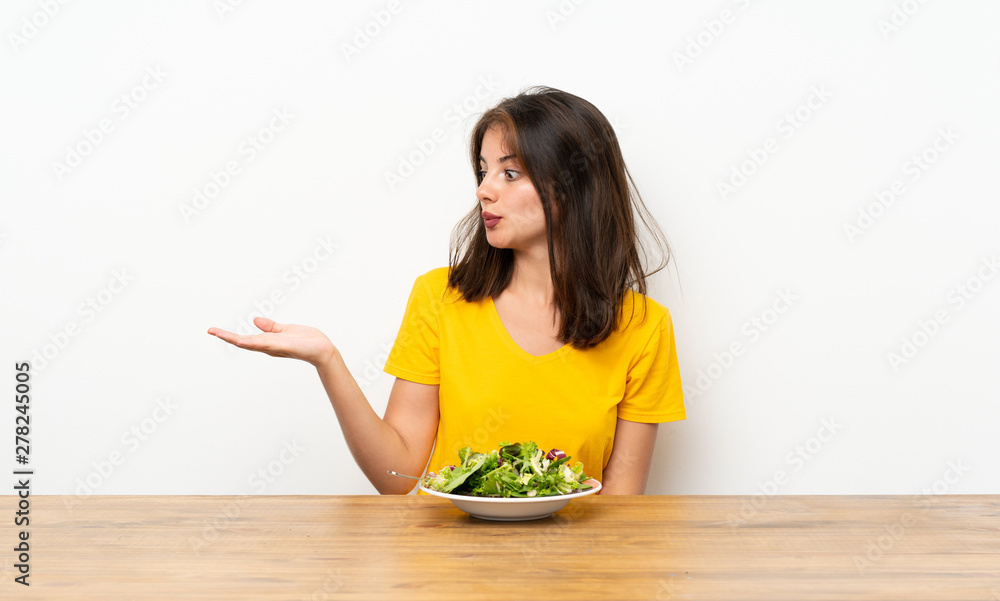 Caucasian girl with salad holding copyspace imaginary on the palm
