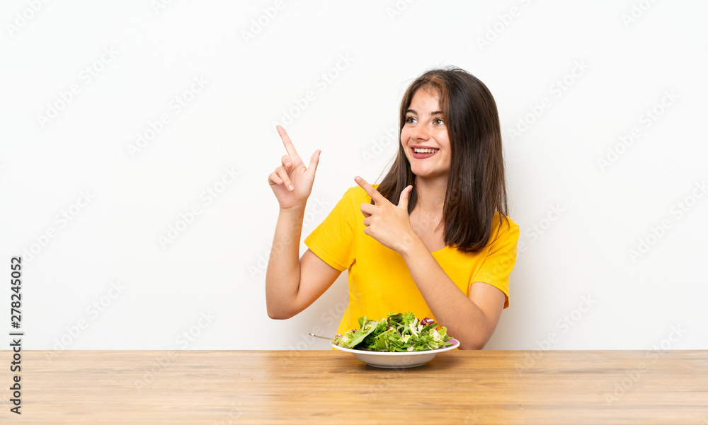 Caucasian girl with salad pointing with the index finger a great idea Caucasian girl with salad pointing with the index finger a great idea