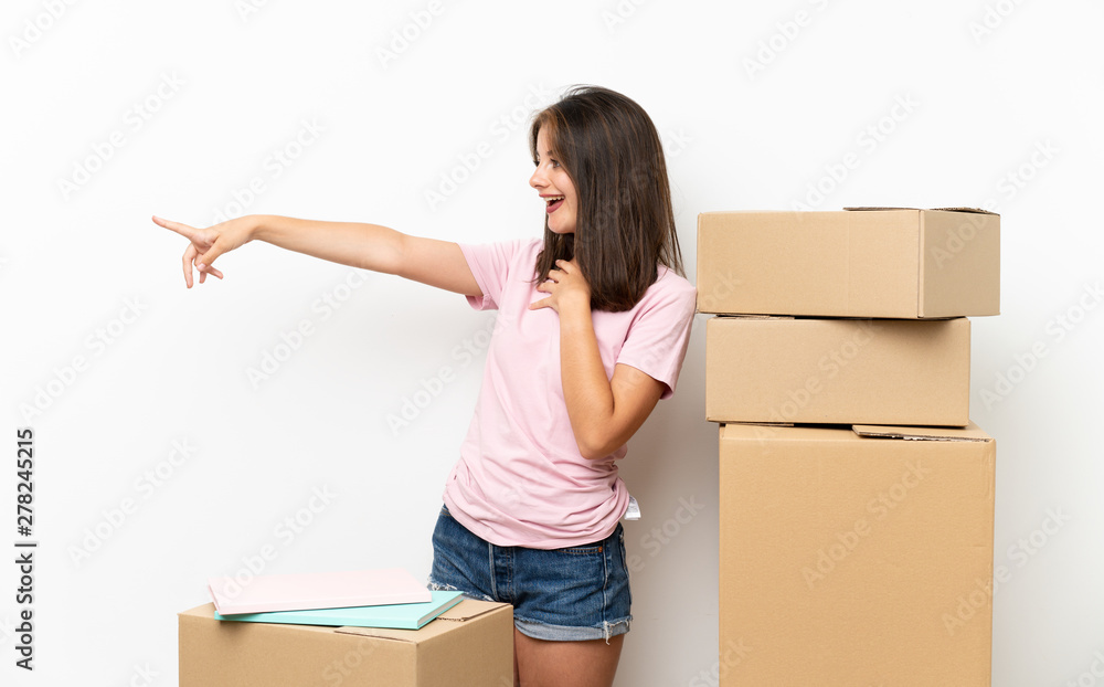 Young girl moving in new home among boxes pointing finger to the side Young girl moving in new home among boxes pointing finger to the side