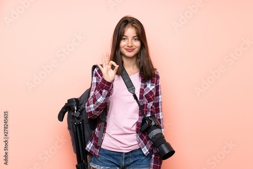 Young photographer girl over isolated pink background showing an ok sign with fingers © luismolinero