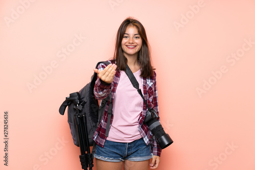 Young photographer girl over isolated pink background inviting to come