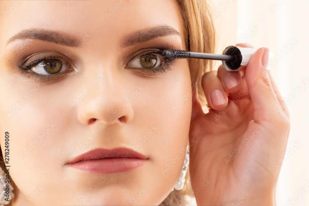 Makeup artist puts makeup on girl model. applies mascara on eyelashes. beautiful girl model, portrait. Nude colors in makeup. wedding, evening makeup. Makeup artist puts makeup on girl model. applies mascara on eyelashes. beautiful girl model, portrait. Nude colors in makeup. wedding, evening makeup.