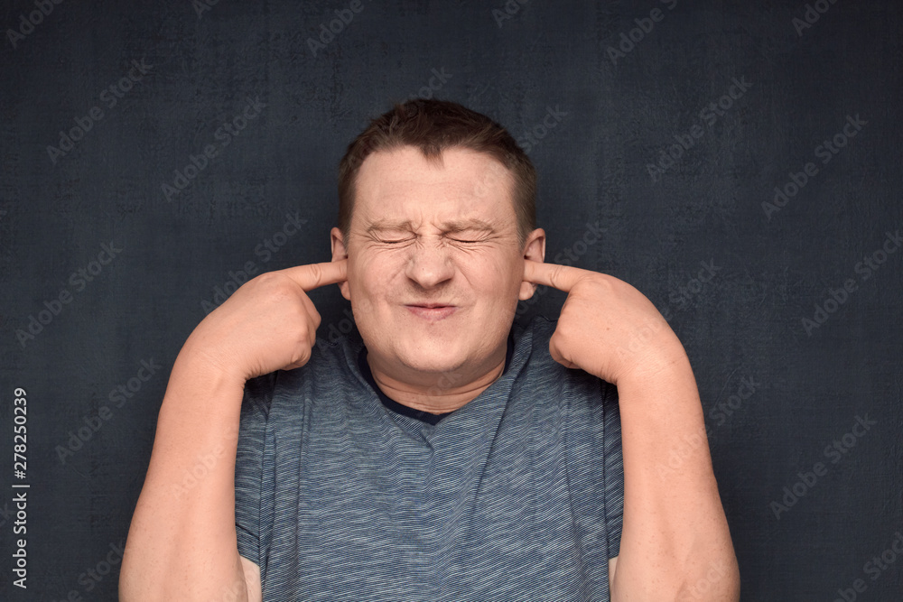 Portrait of displeased man covering ears with index fingers Portrait of displeased man covering ears with index fingers