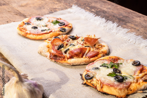 Several ready-made mini pizza, pizzetta on a linen napkin on a wooden table photo