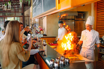 The chef prepares food in front of the visitors in the restaurant