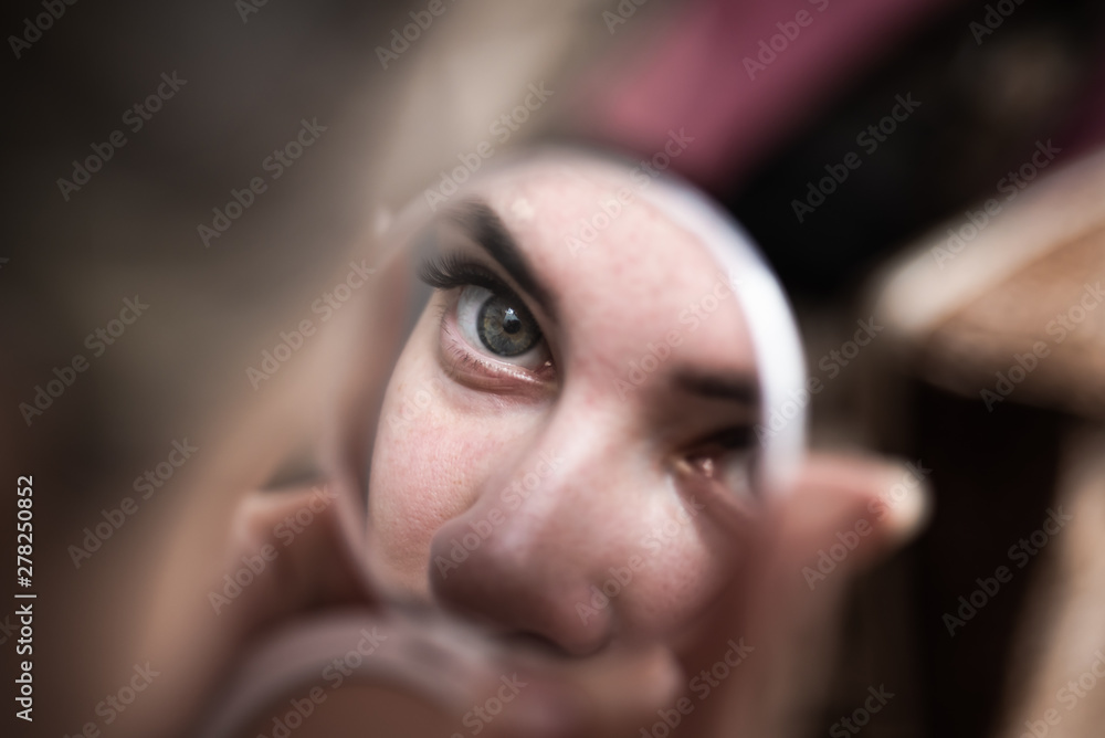 Morning makeup home - a fragment of the face and eyes of a young woman is reflected in a small mirror Morning makeup home - a fragment of the face and eyes of a young woman is reflected in a small mirror