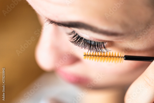 Morning home makeup - woman combing eyelashes, close-up
