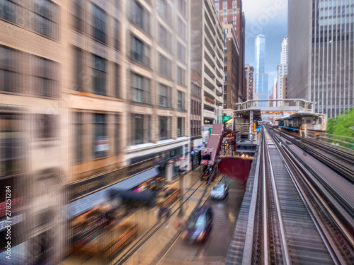 Motion Blur POV from a Moving Train in Chicago, Illinois - with Shops and Cars on the Street Below, and Tall Skyscrapers in the Background © Jon