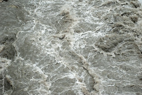 The flow of a mountain rapid river close-up. texture of mountain muddy river,