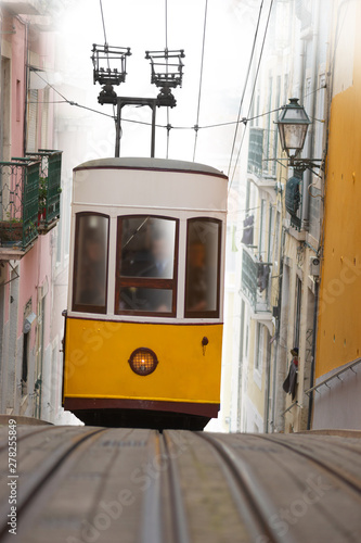 Yellow tram on narrow street on a steep hill in the beautiful city of Lisboa