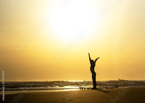 Silhouette of surfer exercsing on beach at sunset photo