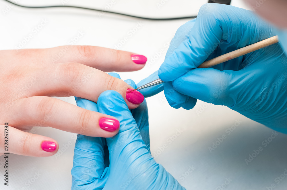 Manicure nail paint pink color. Nail care. Closeup of beautiful woman hands getting manicure in spa salon. Female manicurist cleaning cuticle with professional manicure. Cosmetic procedure. Manicure nail paint pink color. Nail care. Closeup of beautiful woman hands getting manicure in spa salon. Female manicurist cleaning cuticle with professional manicure. Cosmetic procedure.