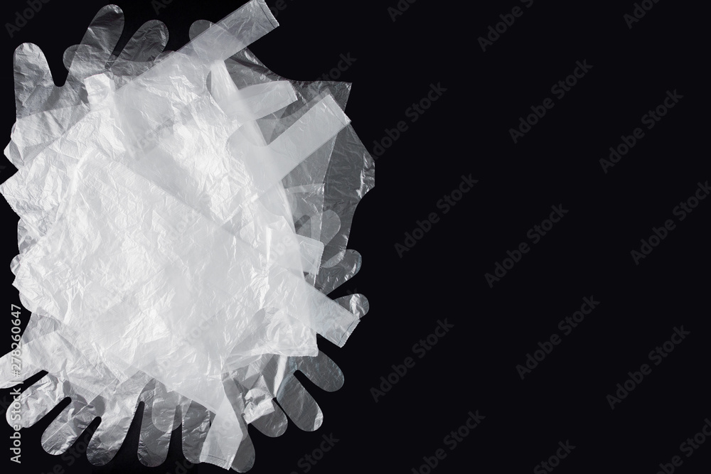 Plastic bag with handles, gloves, on a black background . Used plastic bag for recycling. Concept - ecology, planet pollution with plastic cellophane polyethylene Plastic bag with handles, gloves, on a black background . Used plastic bag for recycling. Concept - ecology, planet pollution with plastic cellophane polyethylene