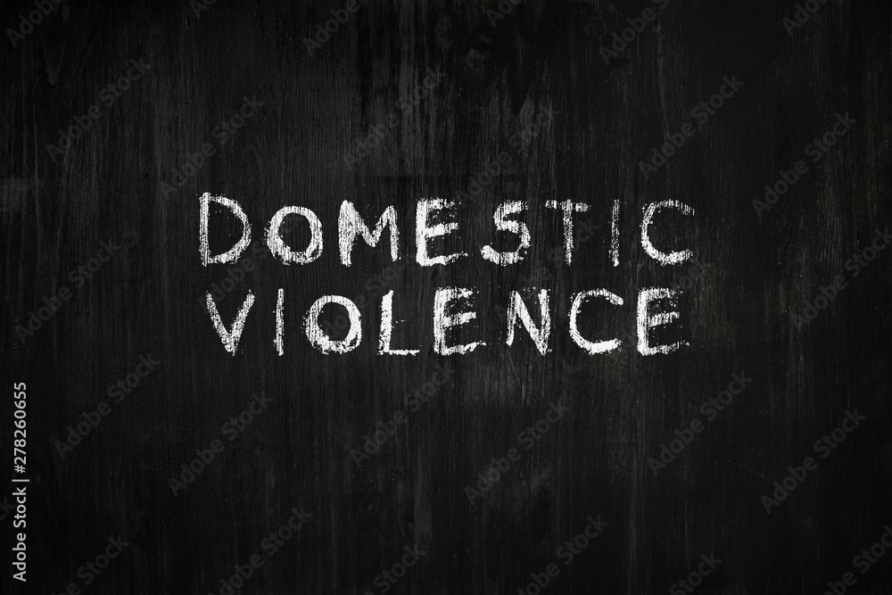Domestic violence phrase handwritten on black wood background. Sign, concept of dealing with behaviour toxic relationship at home or in society