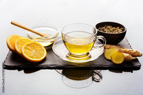 Organic cup of tea with orange slices and ginger next to it.