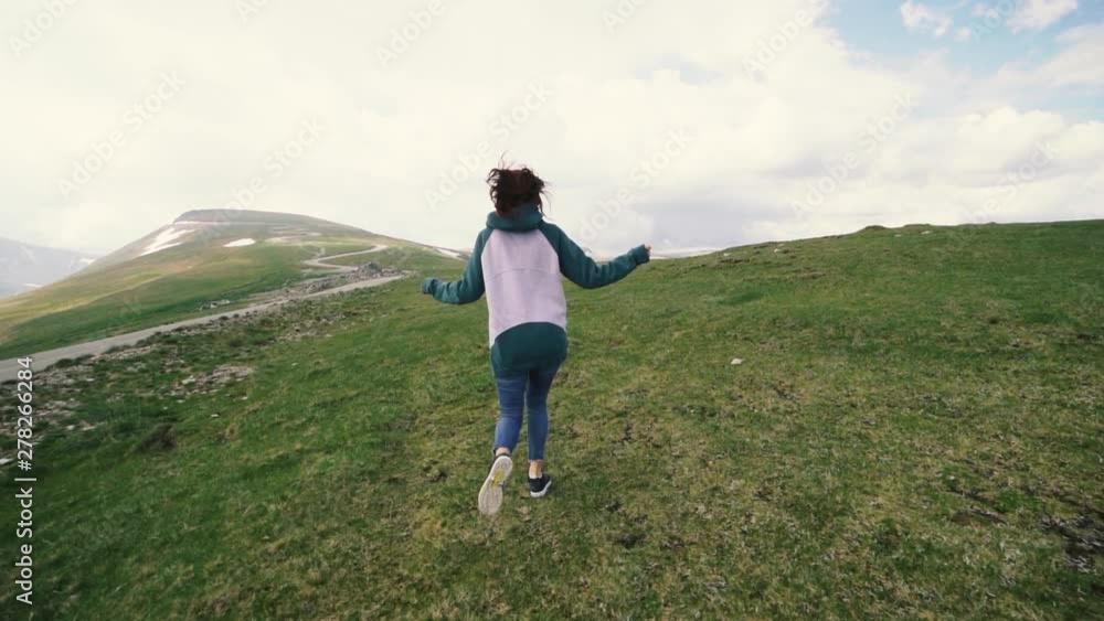 A young woman hiker running and spinning on top of a mountain. Transalpina, Carpathian mountains in Romania slow motion A young woman hiker running and spinning on top of a mountain. Transalpina, Carpathian mountains in Romania slow motion