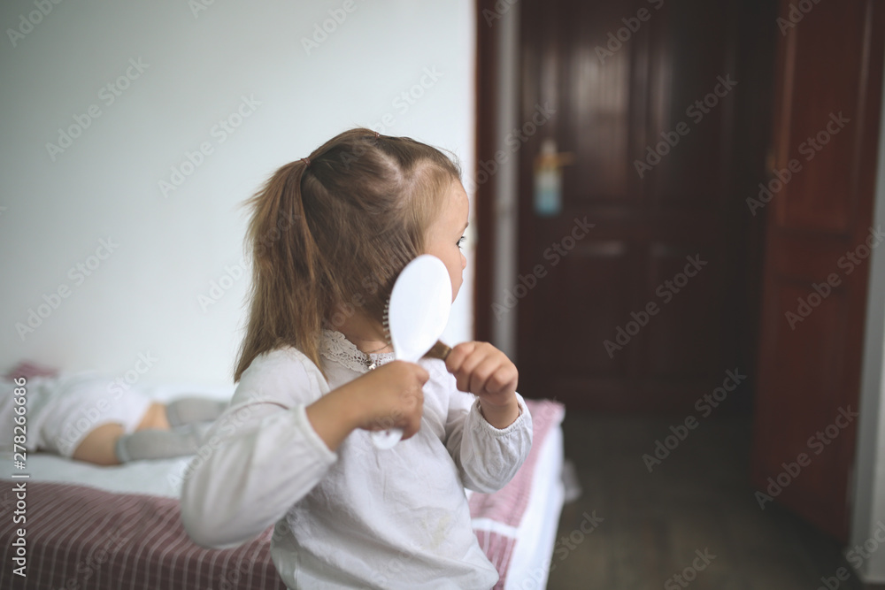 cute caucasian girl child combing hair in the room cute caucasian girl child combing hair in the room
