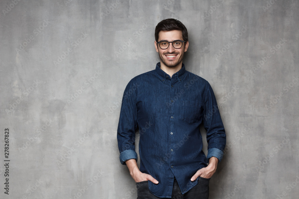 European guy holding hands in pockets looking at camera with friendly smile, isolated on gray background European guy holding hands in pockets looking at camera with friendly smile, isolated on gray background