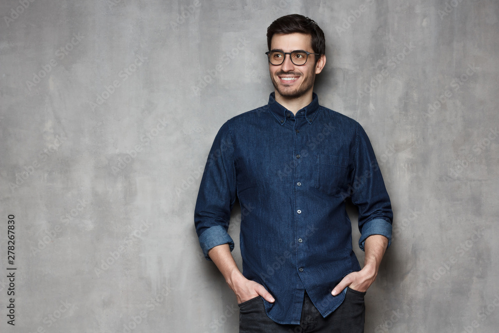 European man in denim shirt with hands in pockets looking aside, copyspace on left European man in denim shirt with hands in pockets looking aside, copyspace on left