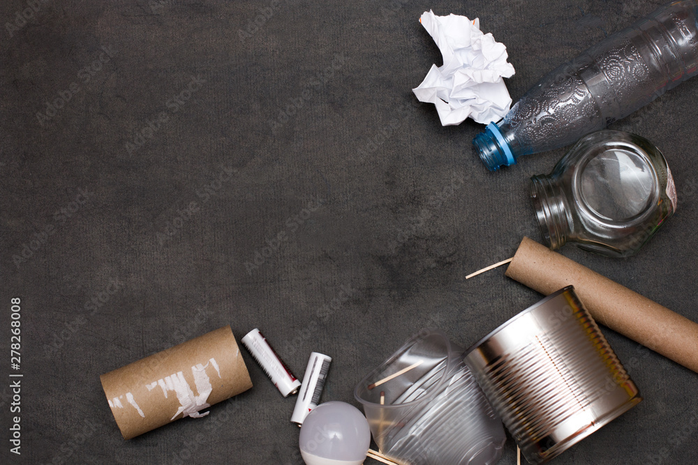 garbage, rubbish on a black background, plastic bottle, cardboard sleeve, light bulb, paper, glass jar, plastic cup, matches, batteries, top view, copy space