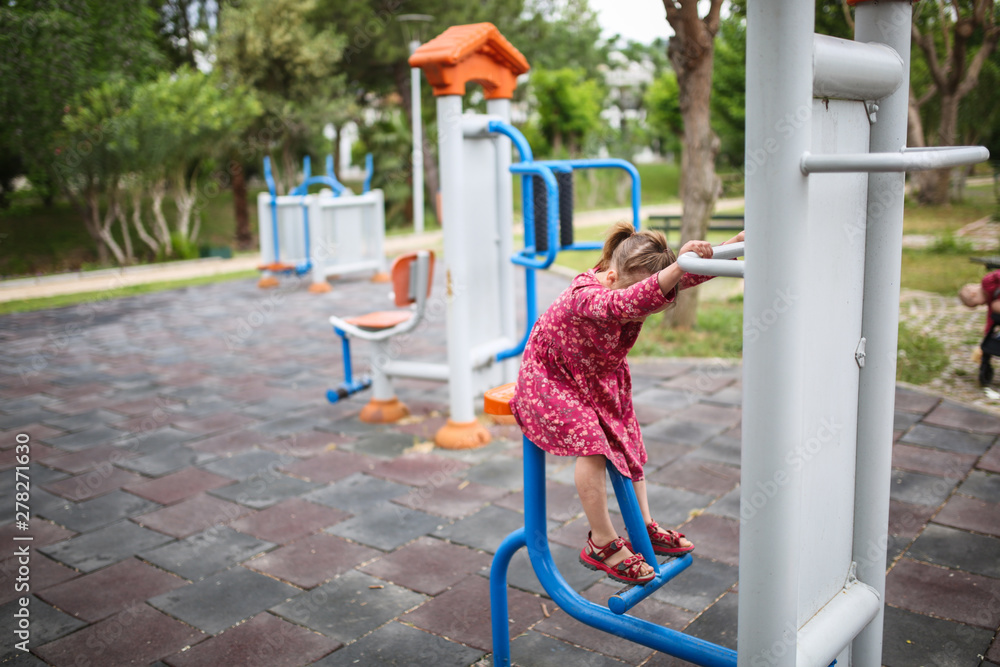 Fototapeta premium Caucasian girl child plays on street gym equipment