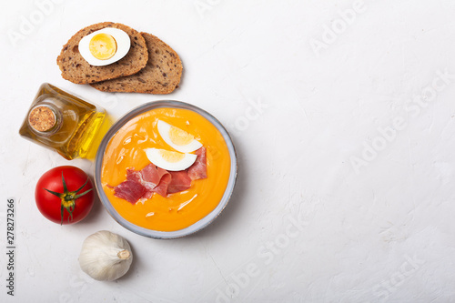 Salmorejo cordobes typical spanish tomato soup similar to the gazpacho, topped with jamon serrano and eggs, white background photo