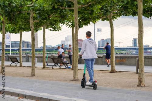 People use and ride E-scooters, trendy urban transportation with Eco friendly mobility concept of sharing Electric Scooter, at promenade riverside of Rhine River.