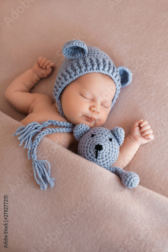 Cute newborn baby girl sleeping with a teddy bear.