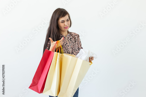 Joyful young brunette woman holding shopping bags posing on a white background with copy space. Concept of discounts and sales in the mall.