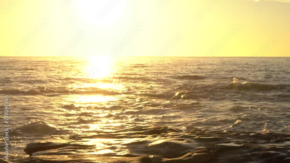 Medium shot of sun reflected in ocean waves before a rocky edge at in the sea. Filmed at Australia, Queensland, Sunshine Coats, Caloundra, Shelly Beach during sunrise Medium shot of sun reflected in ocean waves before a rocky edge at in the sea. Filmed at Australia, Queensland, Sunshine Coats, Caloundra, Shelly Beach during sunrise