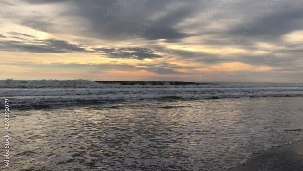 Waves crashing on the shore during sunset in Bali, Indonesia Waves crashing on the shore during sunset in Bali, Indonesia