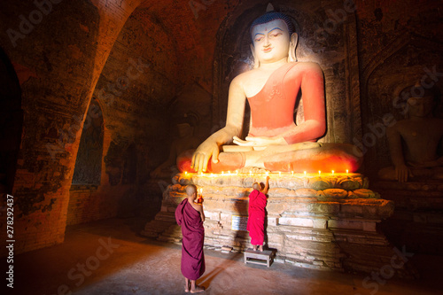 Quadro em tela Monk in Bagan old town pray a buddha statue with candle