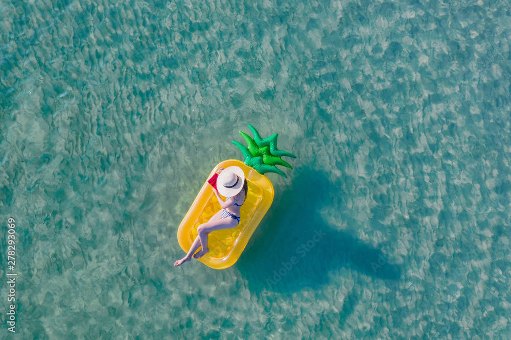 top aerial view of young woman enjoy swimming on floating inflatable tube in sea with cleared water, happy in summertime and vacation or long weekend swimming at sea