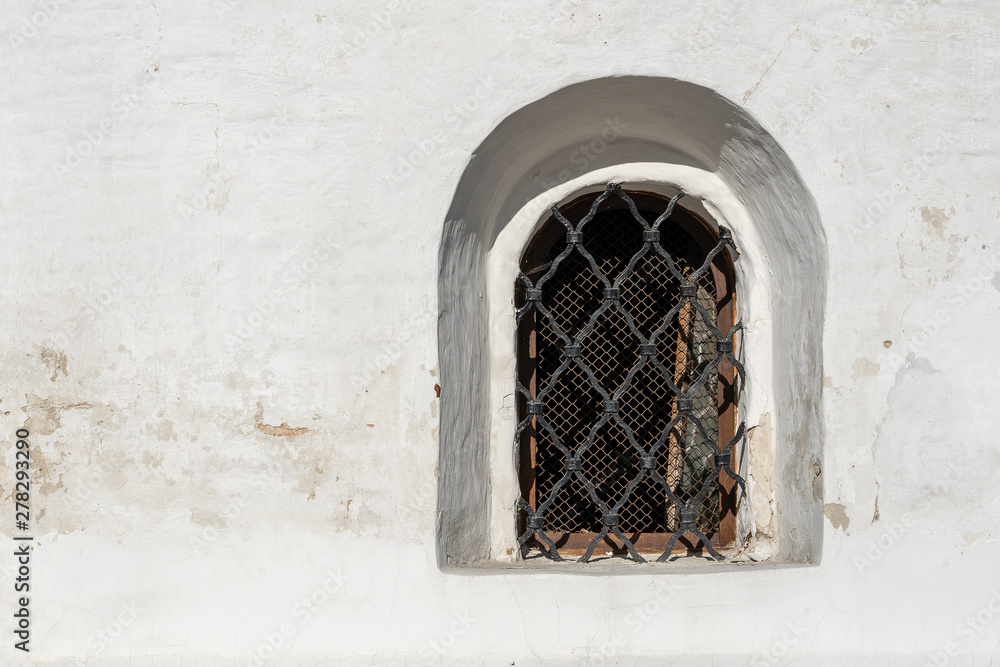Fototapeta premium An ancient window in the white wall. Lattice on the window in the old style. Old-style architecture concept