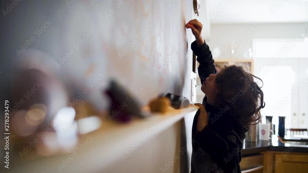 Young boy eagerly drawing on a chalkboard in slow motion Young boy eagerly drawing on a chalkboard in slow motion