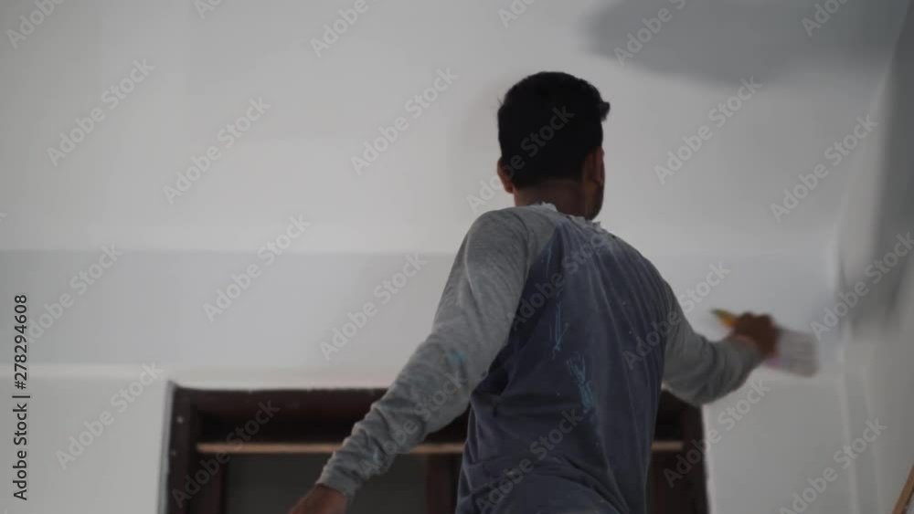 Man making the last adjustments with strokes of white color on wall, above door, India Man making the last adjustments with strokes of white color on wall, above door, India