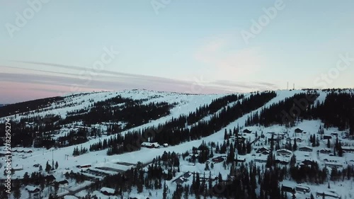 DJI Mavic Pro drone footage from the Swedish ski resort Lindvallen. The drone moves towards the slopes and pans down while rising in altitude. Shot during a colorful dusk soon after sunset. photo