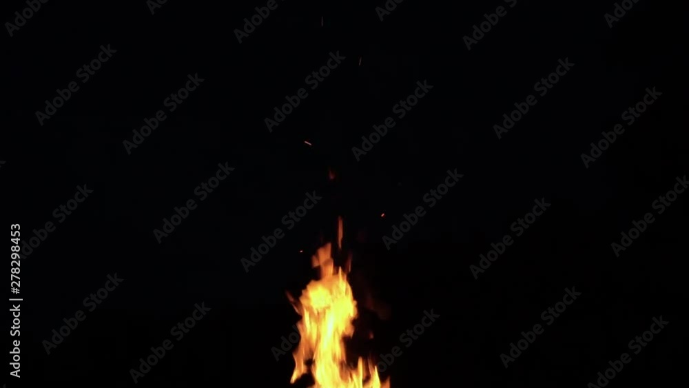 Upwards tilted wide angle shot of flames burning vividly against a black sky while camping at night. Upwards tilted wide angle shot of flames burning vividly against a black sky while camping at night.