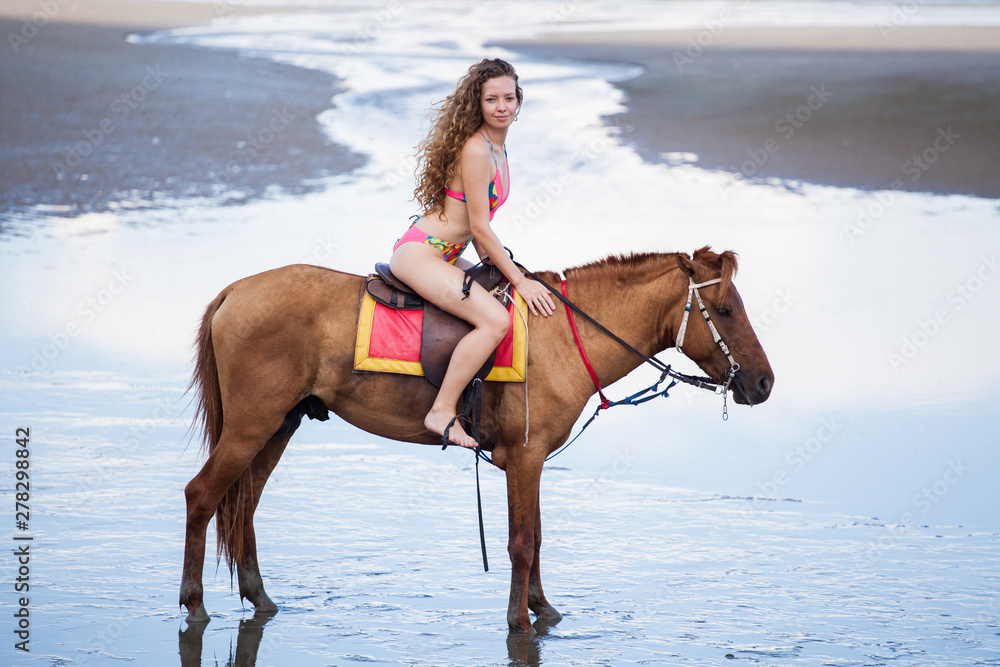 beautiful Young sexy woman wearing bikini riding a horse on the sand . girl in swimsuit outdoor ,sunny day , summer foto de Stock | Adobe Stock