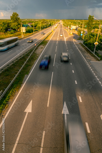 Top view of the road with passing cars on the background of the stormy sky